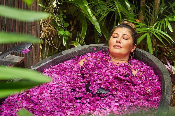 Woman relaxing in flower bath Bliss Bali retreat