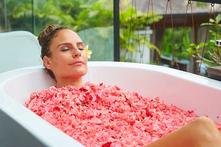 Woman relaxing in flower bath at Bliss Bali retreat