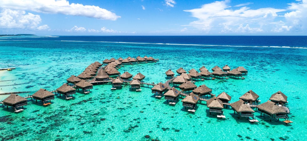 Beach travel vacation Tahiti hotel overwater bungalows luxury resort in coral reef lagoon ocean. Moorea, French Polynesia, Tahiti, South Pacific Ocean.